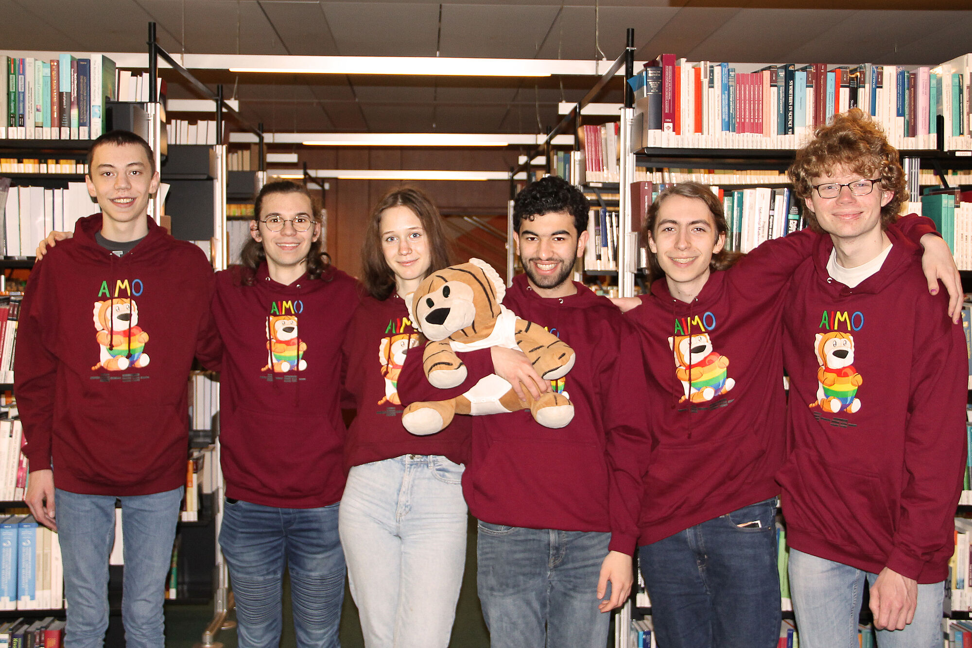 Die sechs Mitglieder des deutschen Teams bei der IMO 2024, alle in rostroten Pullovern mit MathemaTigerin-Aufdruck. 